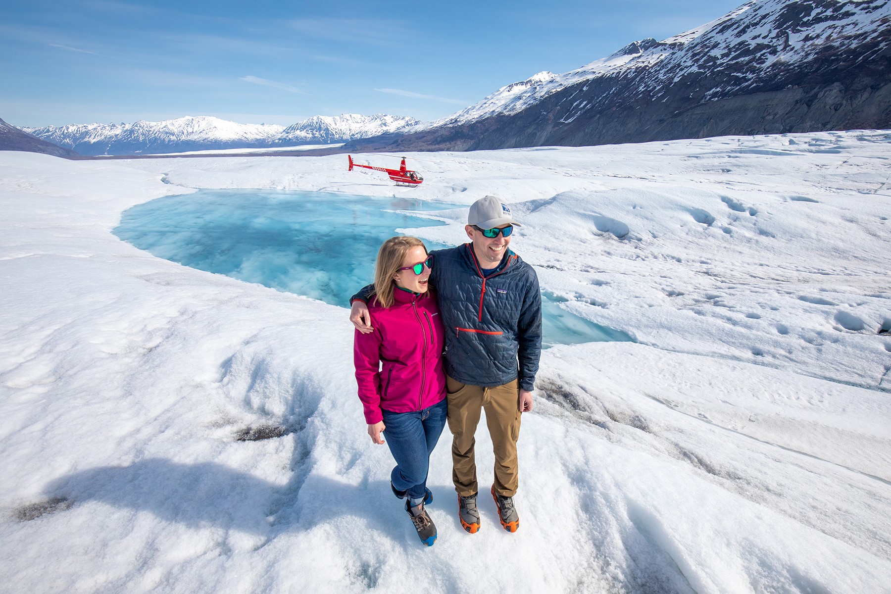 Couple on glacier with helicopter in background
