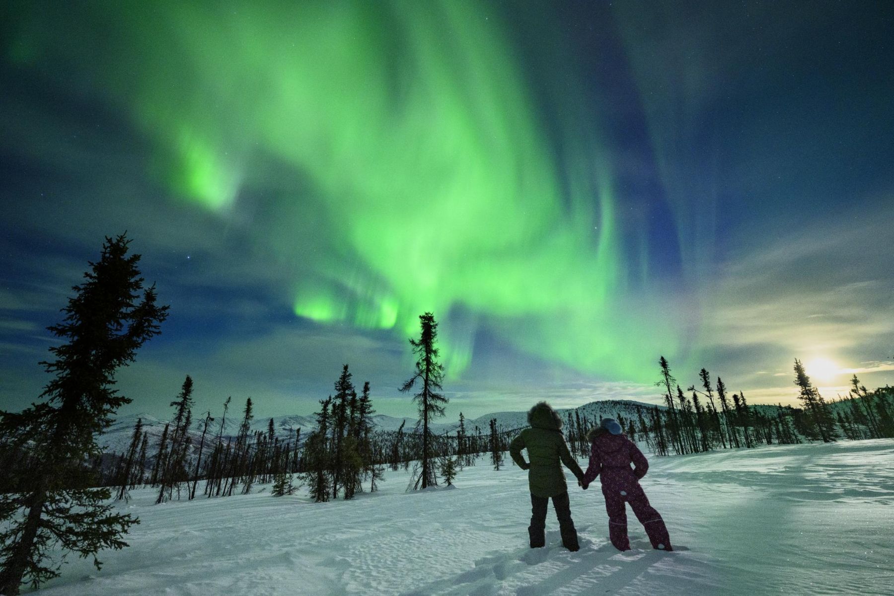 Two people holding hands while viewing the northern lights in Fairbanks