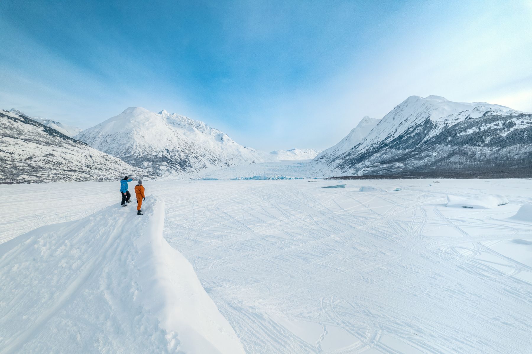 Two people viewing a Spencer Glacier on a snowmachine tour