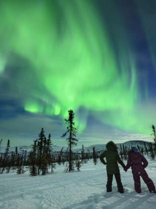 Two people holding hands while viewing the northern lights in Fairbanks