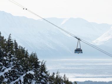 Tramway car rising over a mountain and sea background