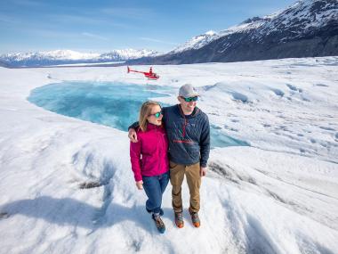 Couple on glacier with helicopter in background